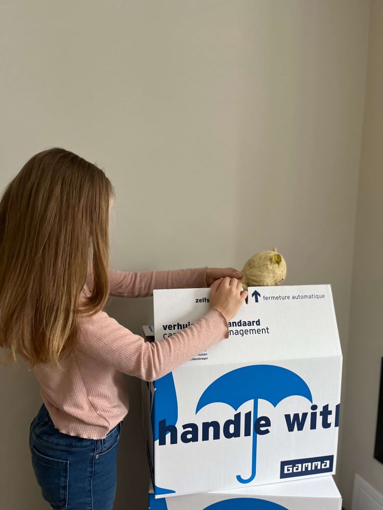 een kind die verhuisdozen inpakt